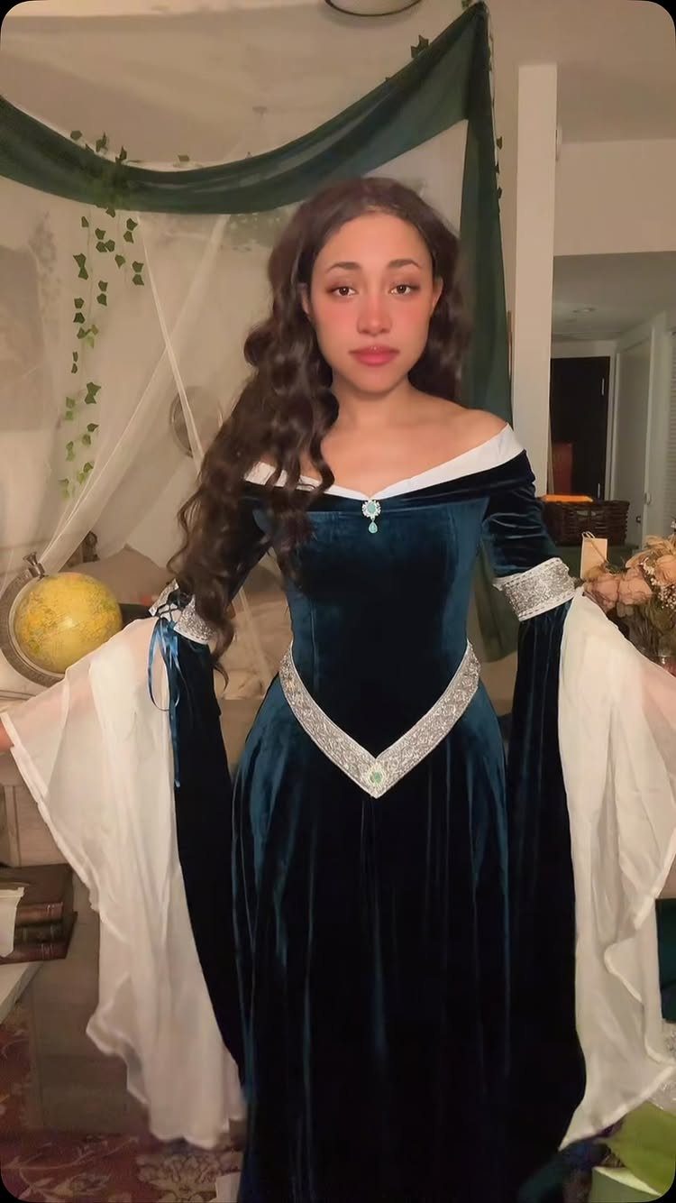 Woman wearing a dark teal velvet Renaissance dress with wide white sleeves