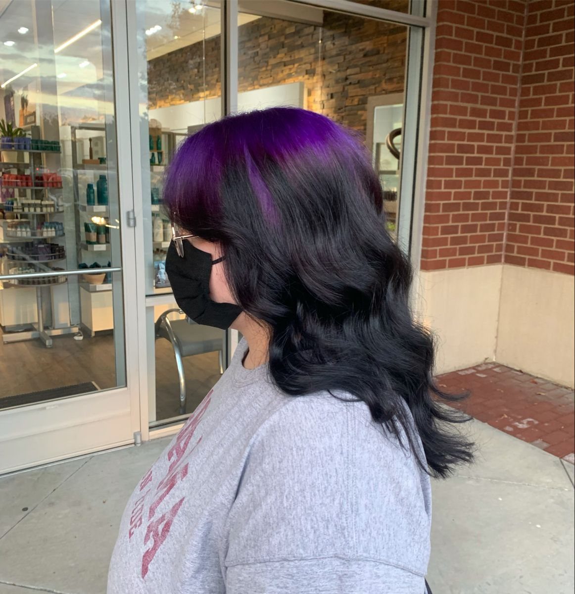 Long wavy hair with dark violet roots transitioning to black ends.