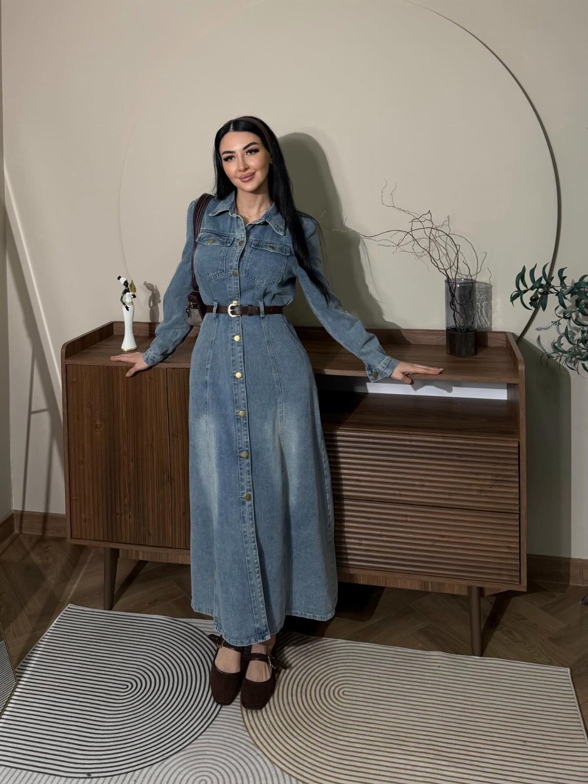 Denim Fitted Dress: 7 Ideas, From Mini to Midi 2 Woman in a light-wash denim button-down maxi dress with a brown belt.