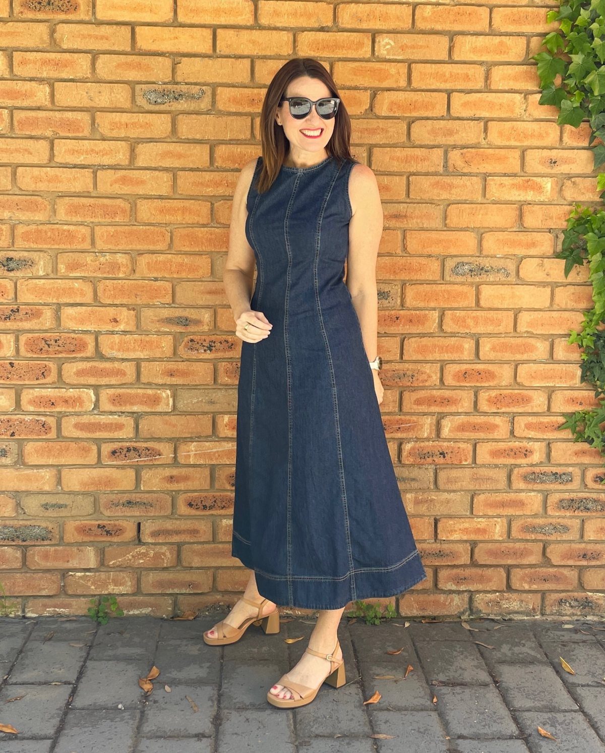 Denim Fitted Dress: 7 Ideas, From Mini to Midi 4 Woman in a sleeveless dark blue denim midi dress standing by a brick wall