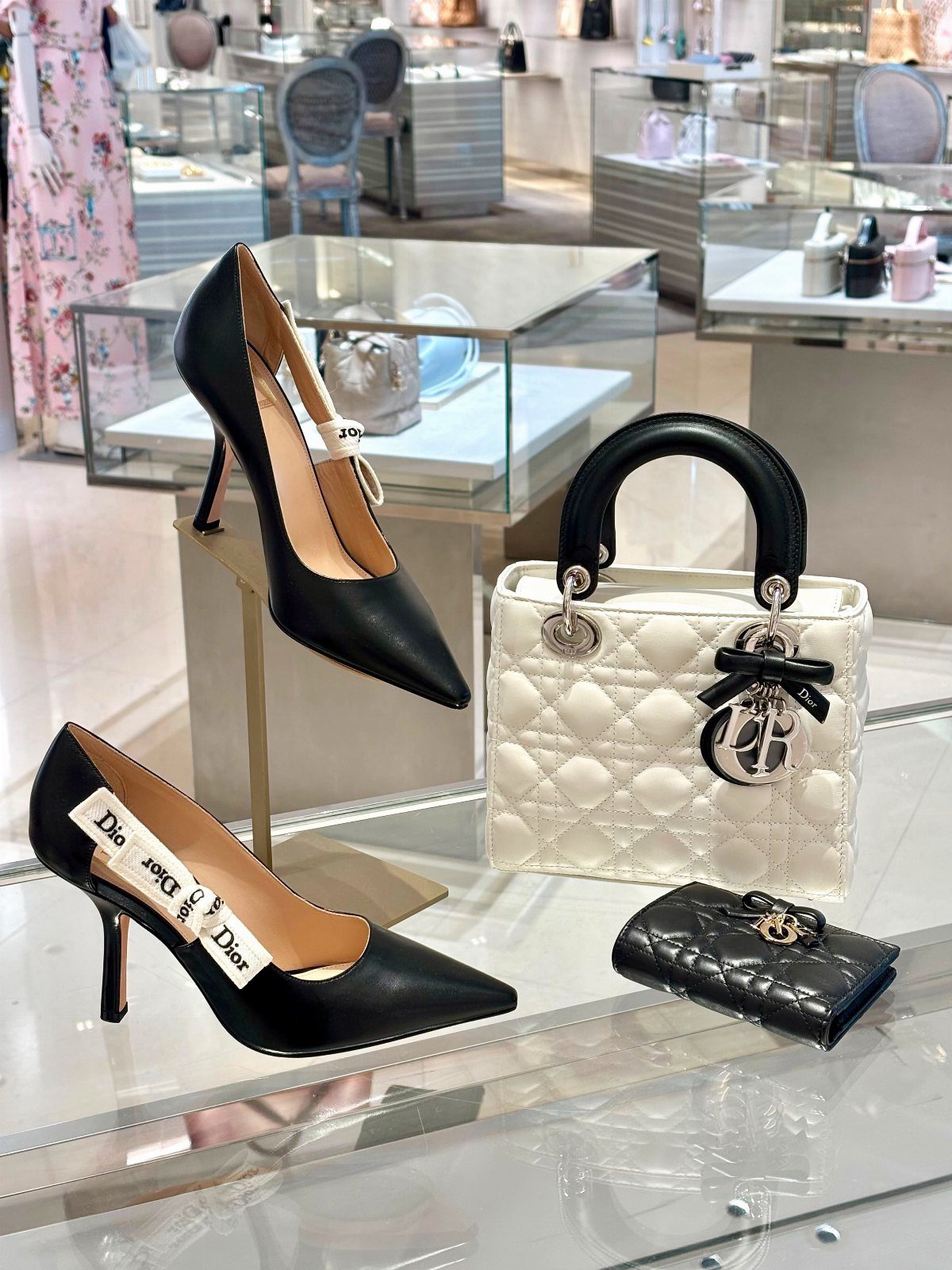 Black leather pointed-toe pumps and a white quilted handbag in a luxury store.