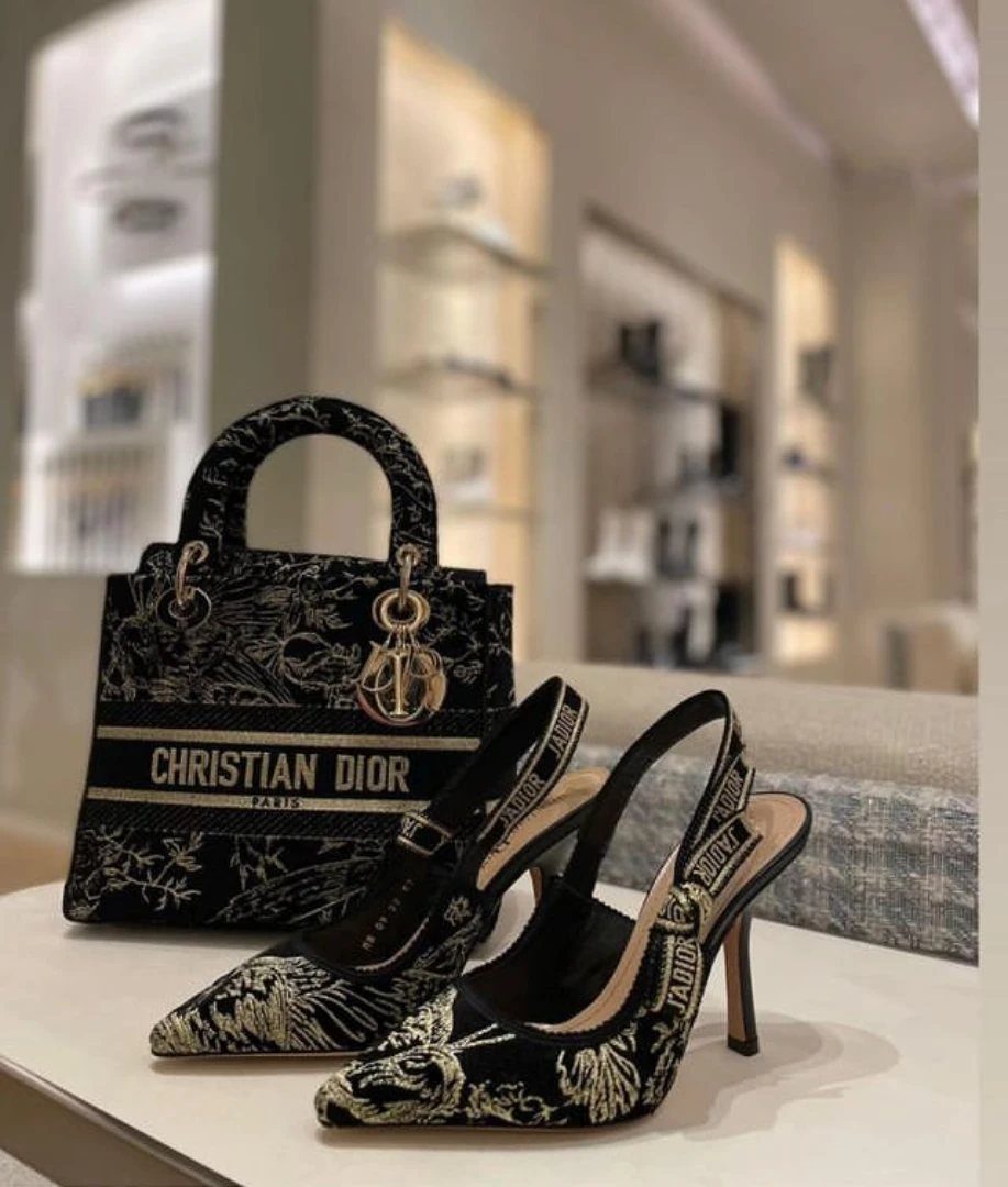 Black and gold Dior slingback heels and matching handbag in a luxury boutique.