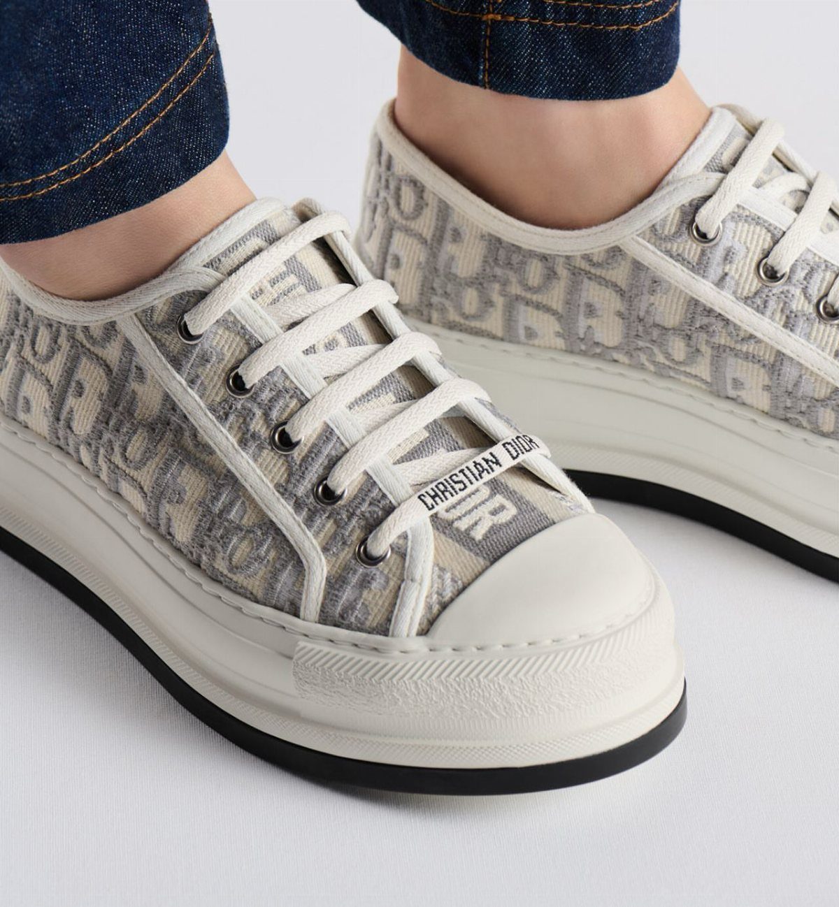 Dior Walk'n'Dior sneakers with monogram pattern and white soles worn with blue jeans.