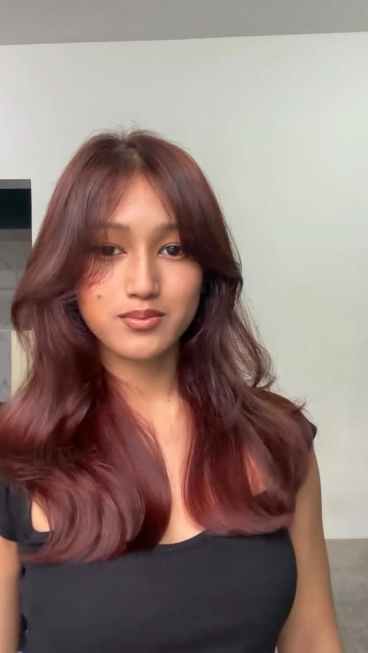 Different Shades of Red Hair Dye: 15 Looks, Copper to Crimson 9 Woman with long wavy cinnamon red hair wearing a black top.