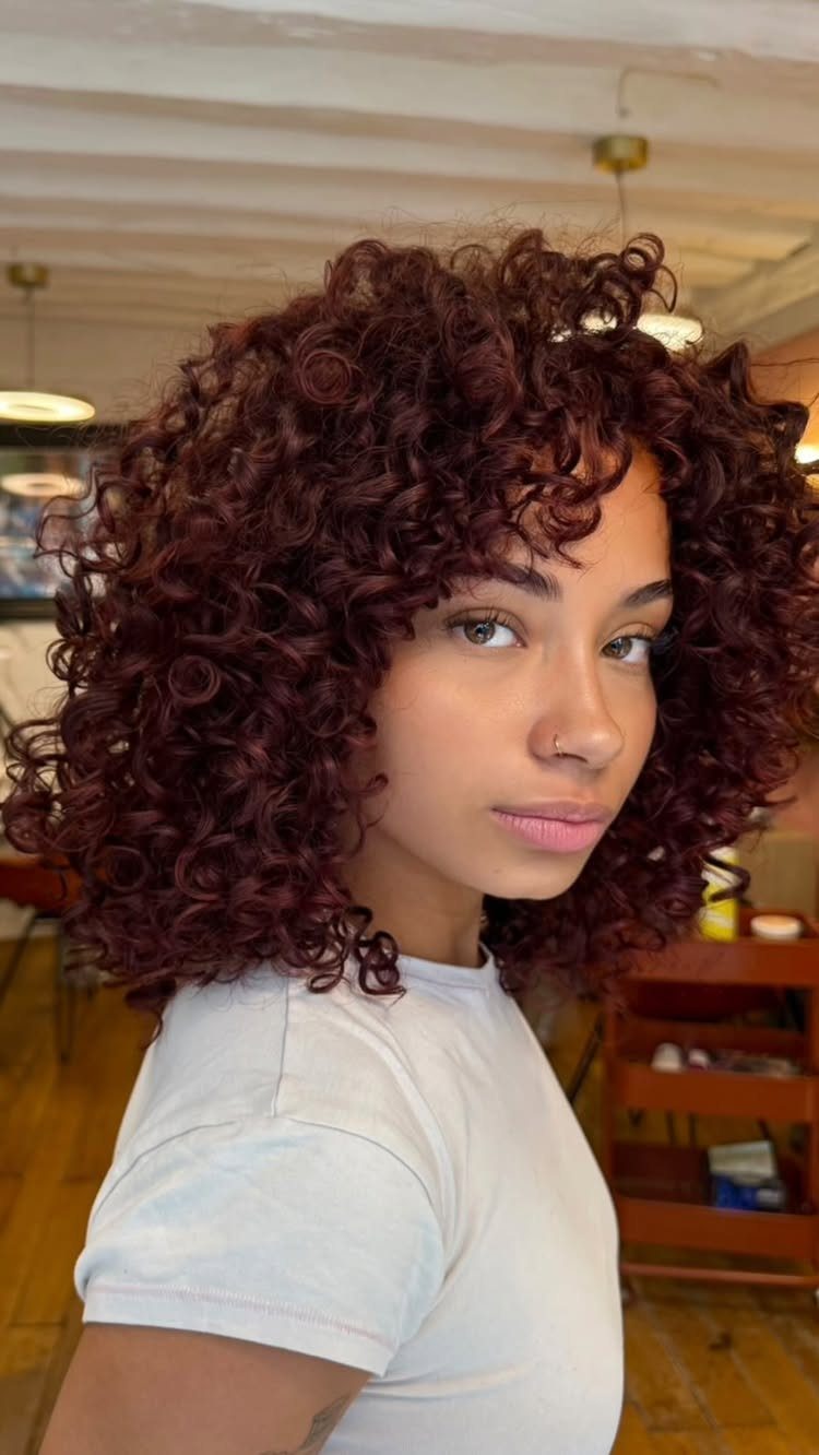 Different Shades of Red Hair Dye: 15 Looks, Copper to Crimson 13 Woman with voluminous curly hair dyed a deep mahogany red wearing white shirt