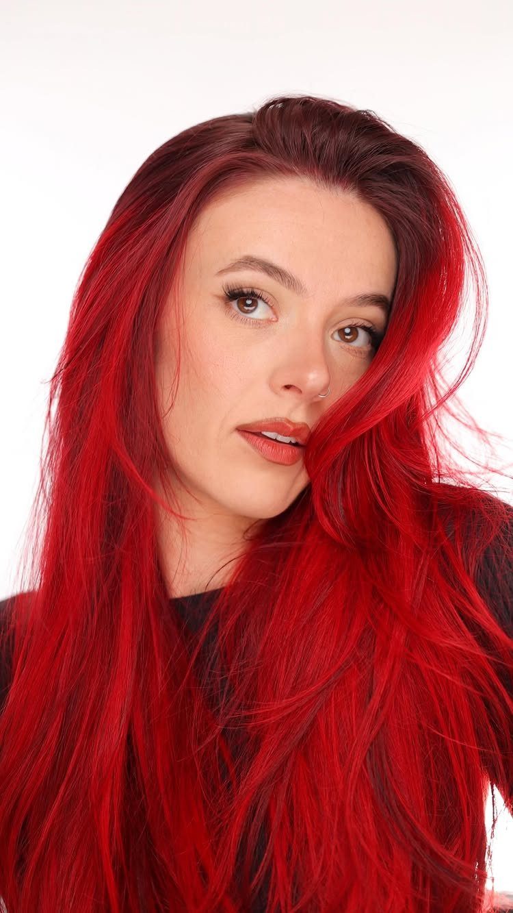 Different Shades of Red Hair Dye: 15 Looks, Copper to Crimson 8 Woman with long, vibrant true red hair and matching lipstick against white background