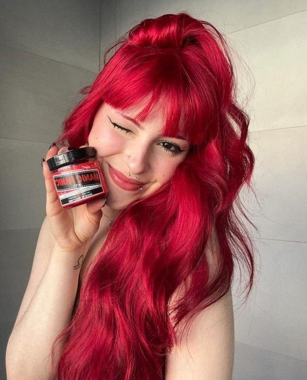 Different Shades of Red Hair Dye: 15 Looks, Copper to Crimson 11 Woman with vibrant red hair holding a jar of red hair dye