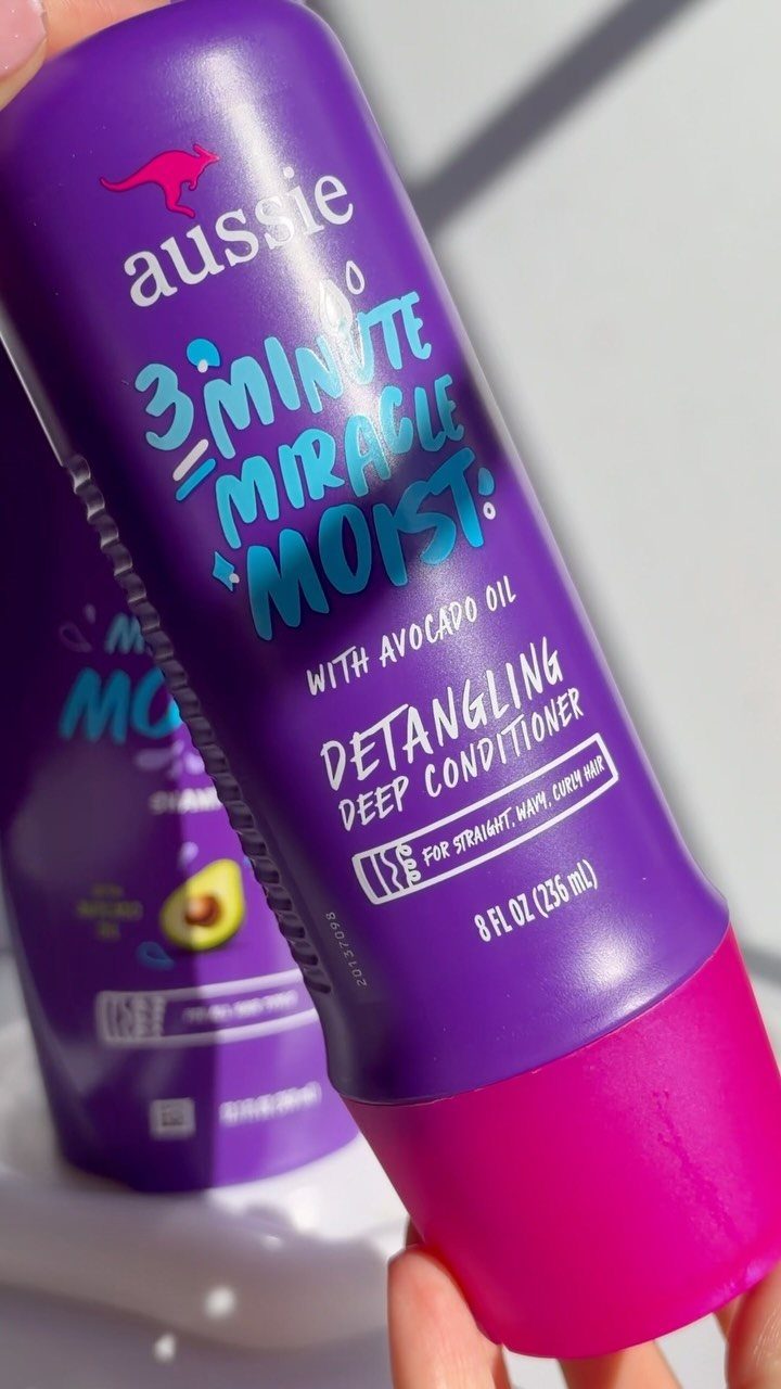 Aussie 3 Minute Miracle Moist deep conditioner bottle held in a person's hand.