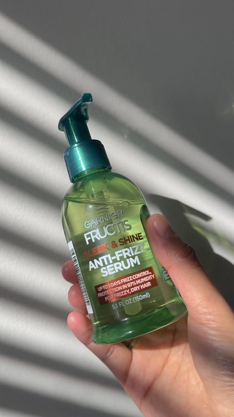 Garnier Fructis Sleek & Shine Anti-Frizz Serum bottle held in a person's hand.