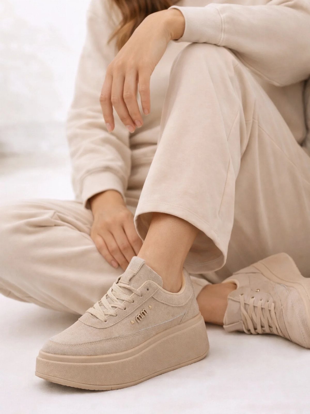 Fancy Sneakers for Women: 9 Ideas, From Retro to Platform 7 Beige platform sneakers worn with matching beige sweatpants on a white background