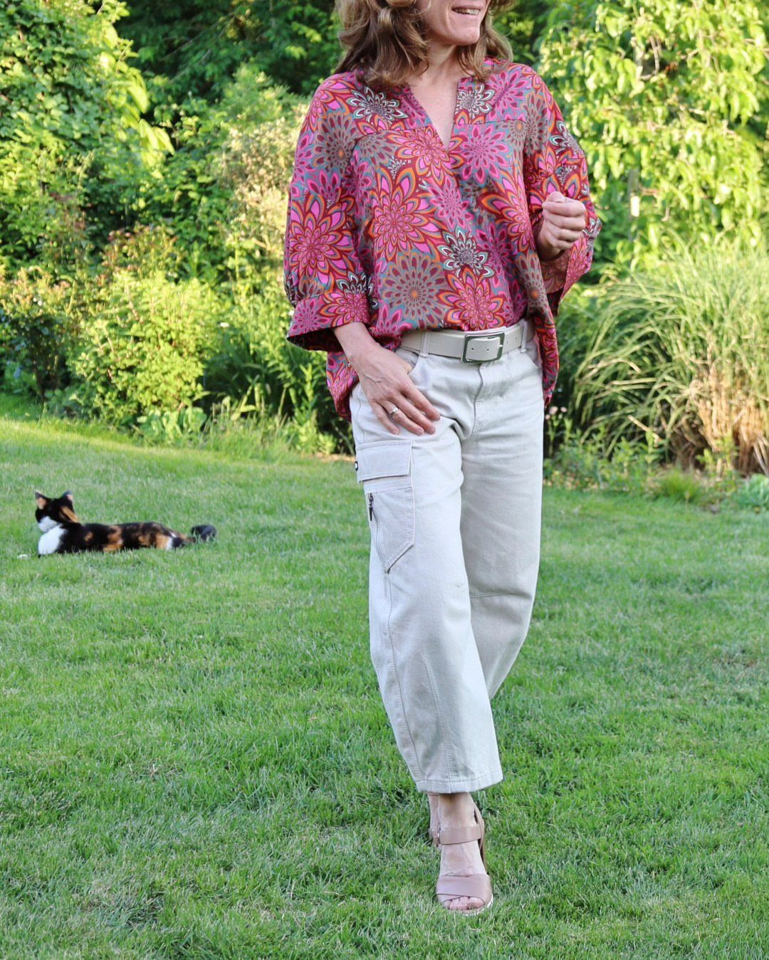 Gillian Practical Magic Outfits: 11 Ideas to Wear Now 10 Woman wearing a patterned red blouse and beige cargo pants in a garden
