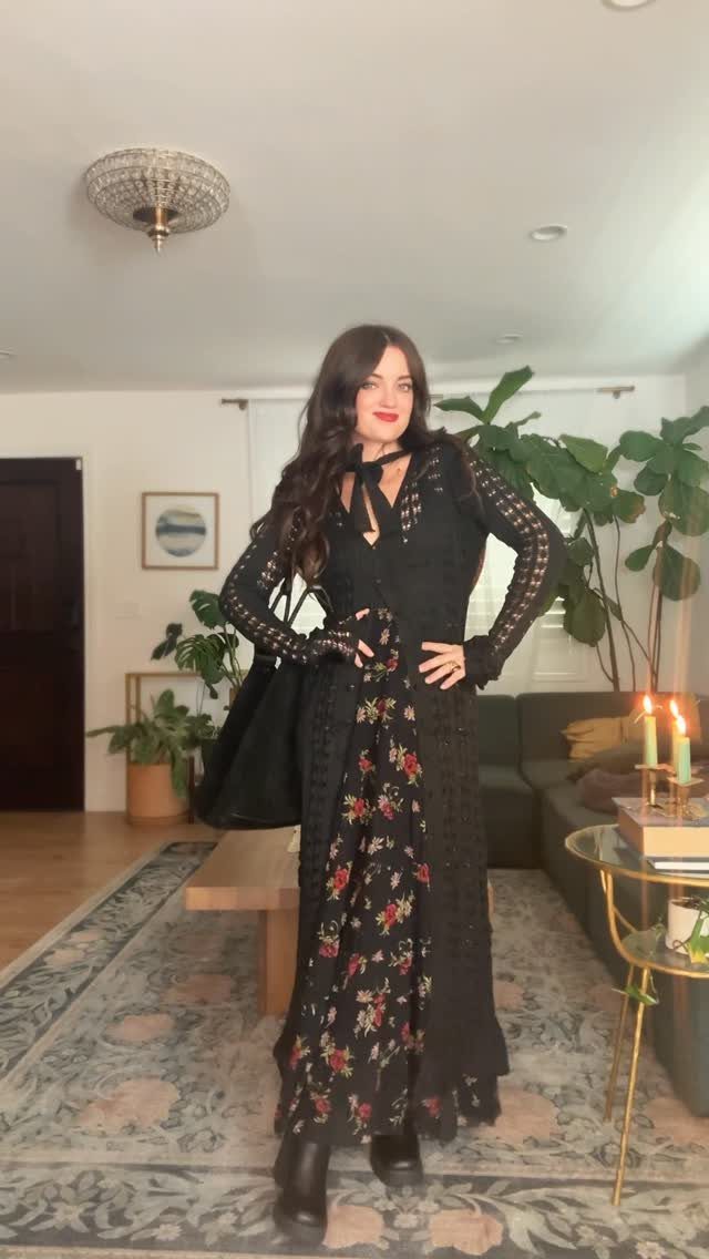 Gillian Practical Magic Outfits: 11 Ideas to Wear Now 8 Woman wearing a black lace cardigan and floral maxi dress in a living room.