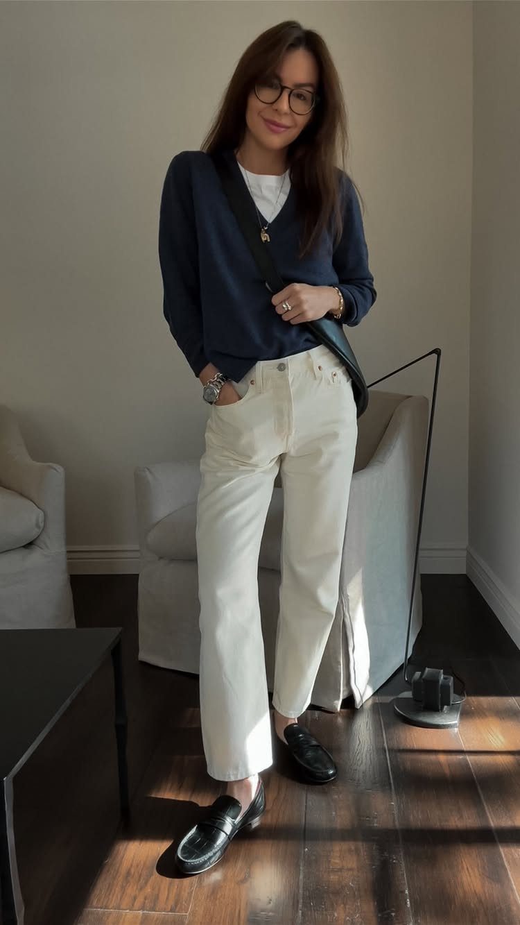 Gillian Practical Magic Outfits: 11 Ideas to Wear Now 2 Woman wearing a navy oversized sweater and wide-leg cream jeans with black loafers.