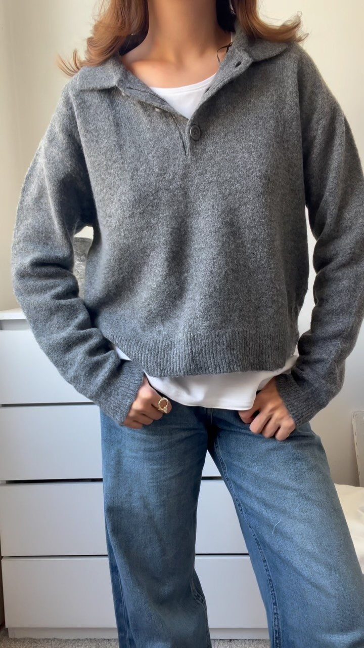 Gray knit polo shirt layered over a white t-shirt with blue denim jeans.