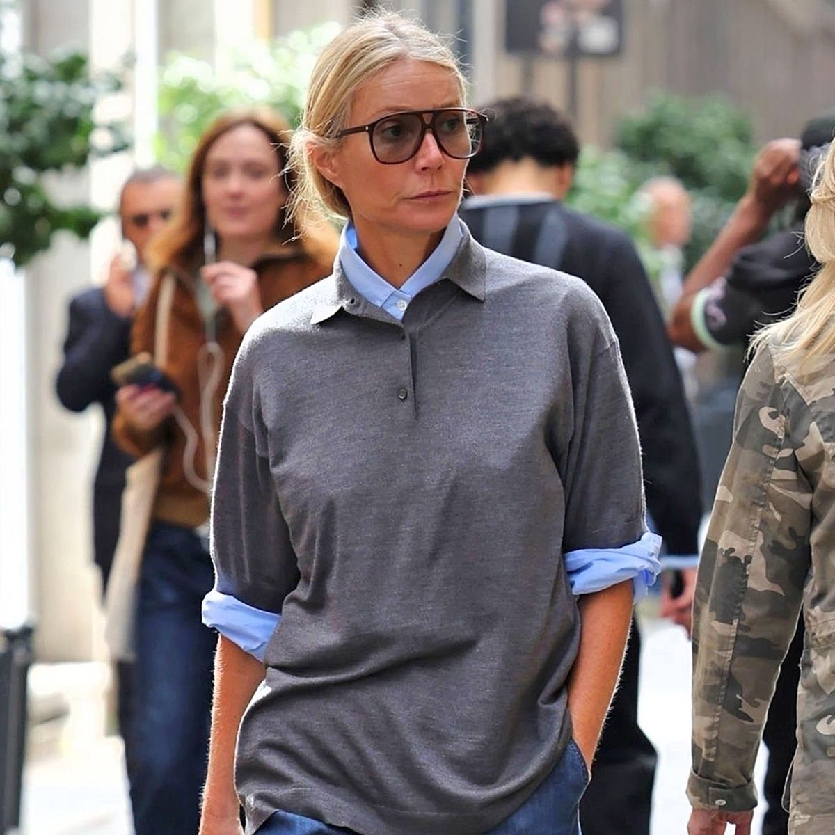 Woman wearing a gray polo shirt layered over a light blue button-down shirt.