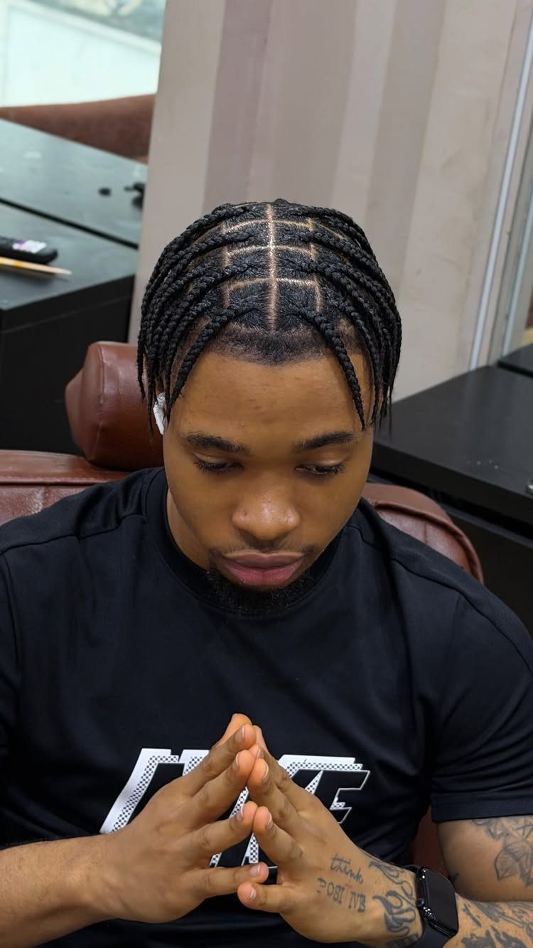Man with black box braids and square parting wearing a black t-shirt.