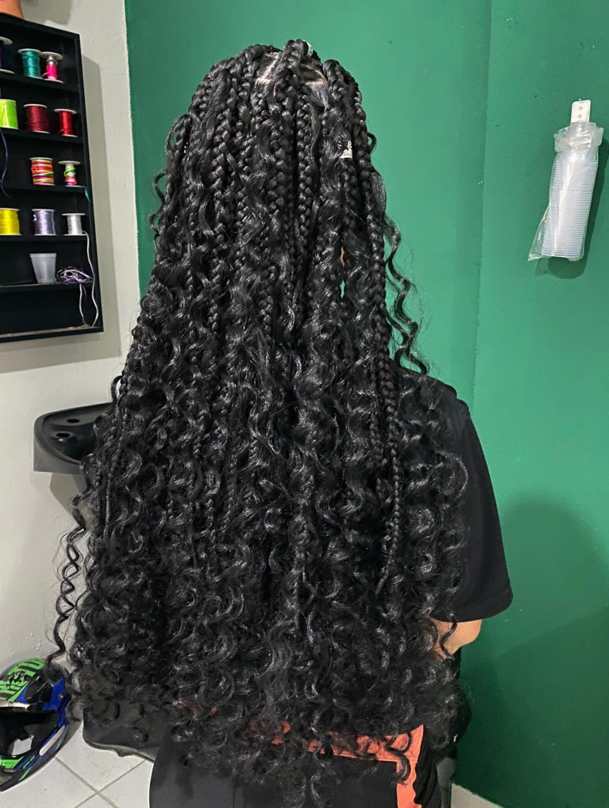 Long black braided hair with curly ends seen from the back.