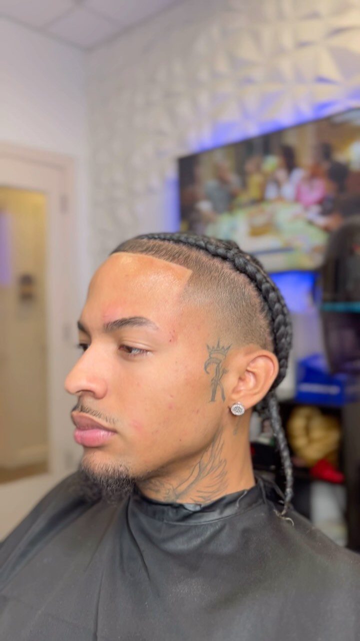 Man with cornrows on top and a high skin fade in a barbershop