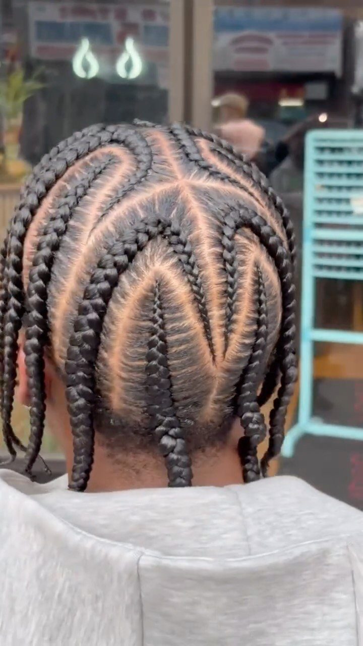 Man's head with black hair styled in geometric star-patterned cornrow braids.