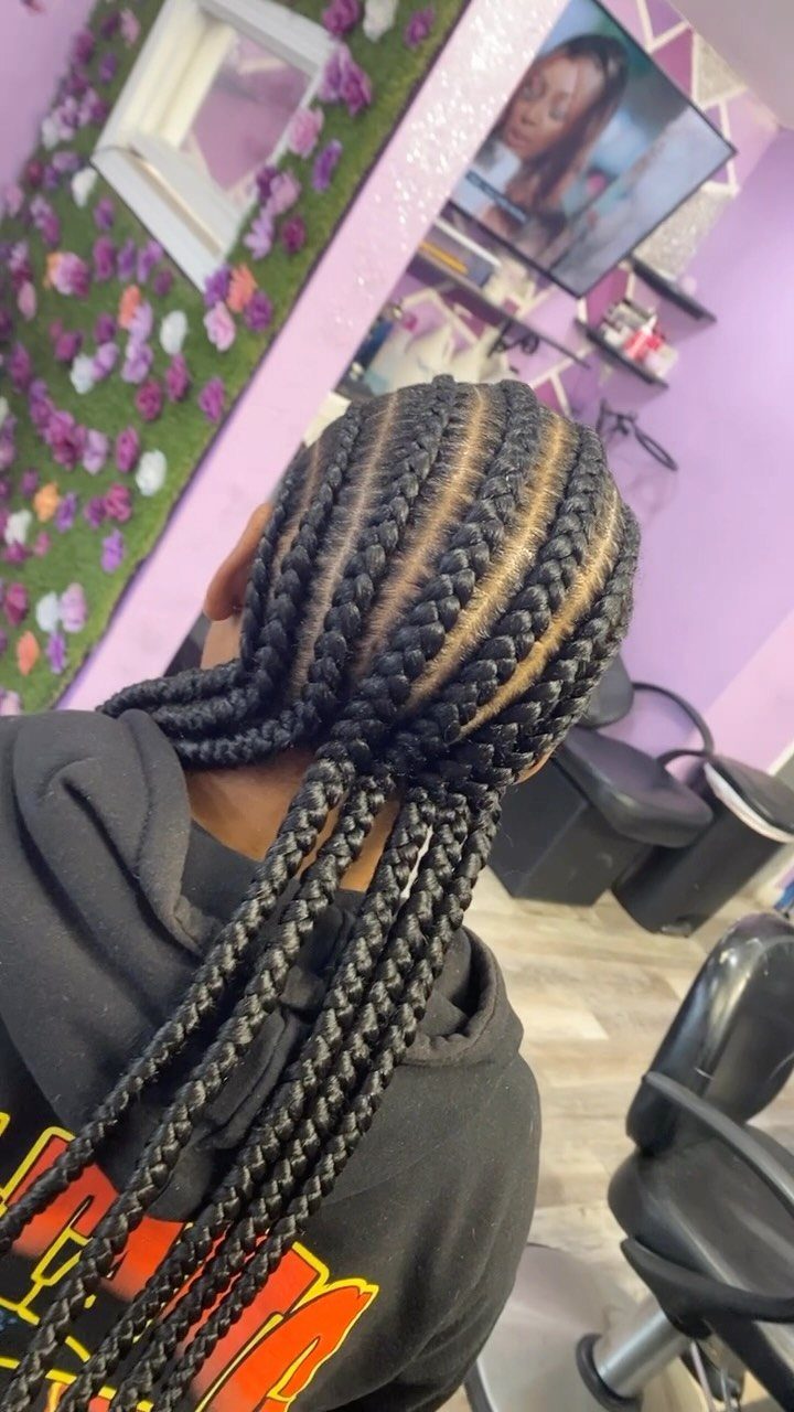 Man with long dark hair styled in straight back cornrow braids from behind.