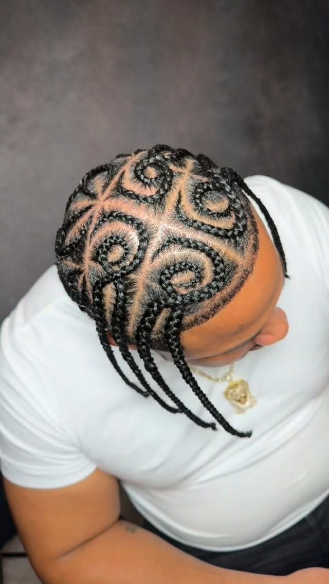 Man with intricate swirling cornrow braids forming circular patterns on his head.