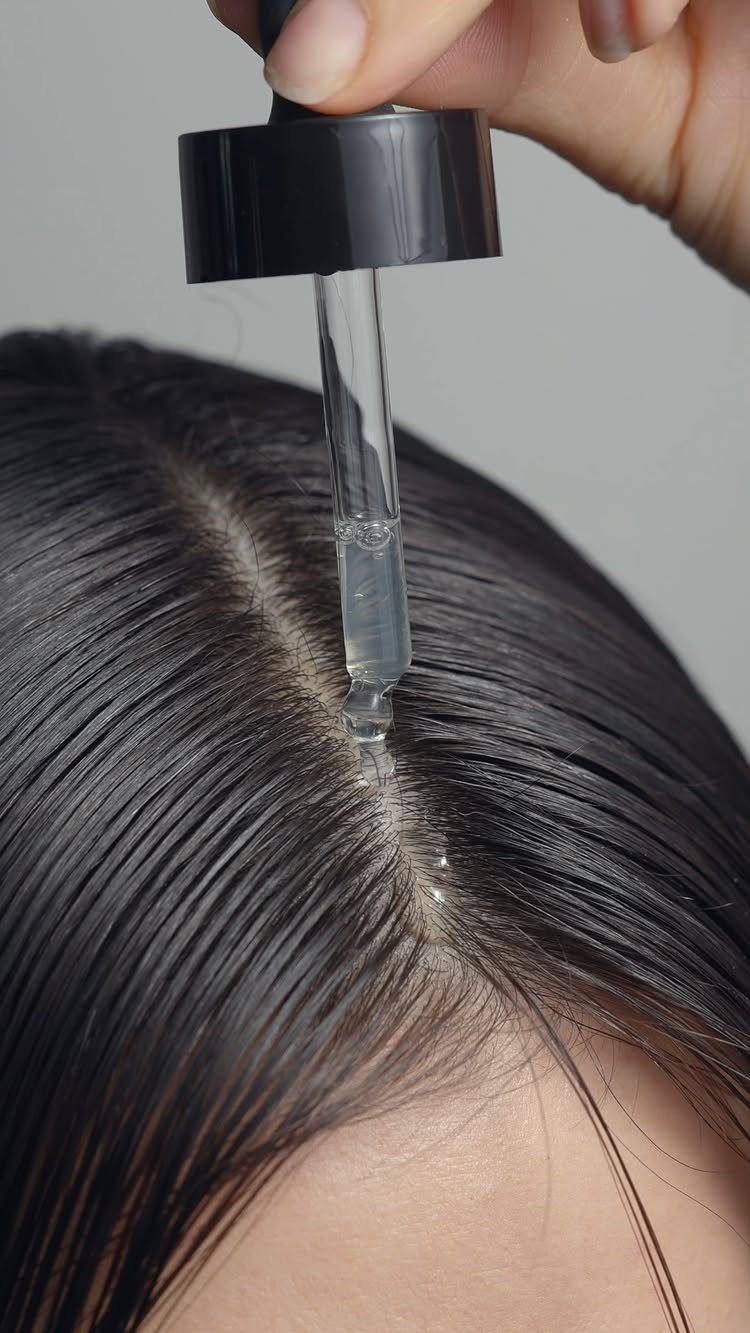Hair Care at Home: 7 Ideas for Softer, Smoother Hair 6 Glass dropper applying clear hair oil to the scalp of dark hair