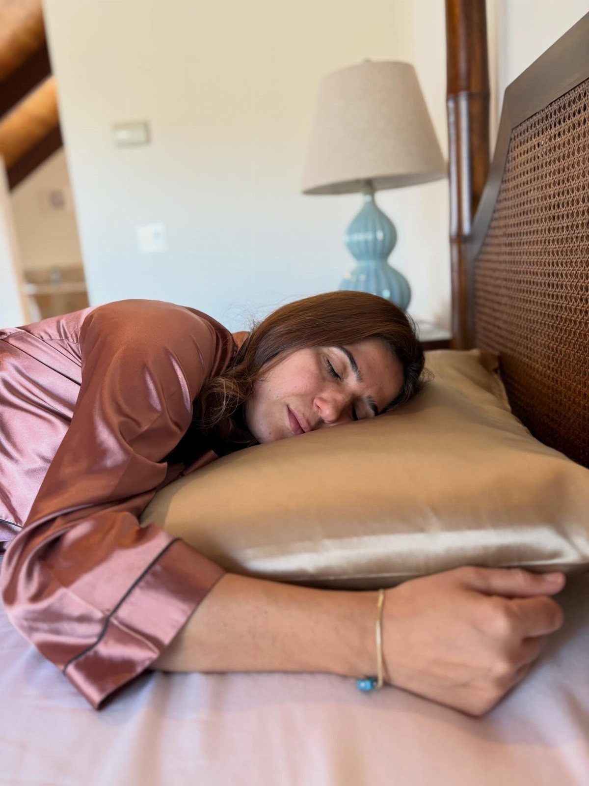 Hair Care at Home: 7 Ideas for Softer, Smoother Hair 3 Woman sleeping on a gold silk pillowcase wearing a satin robe in bedroom