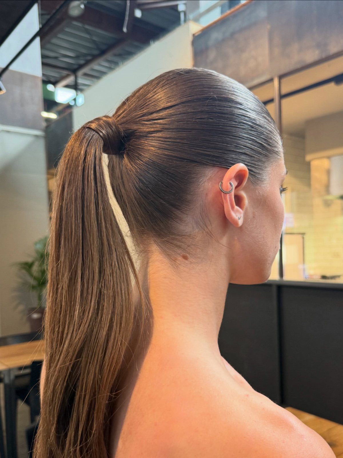 Hair Up Styles to Try: 12 Buns, Ponytails and More 8 Woman with brown hair in a polished, slicked-back high ponytail side view