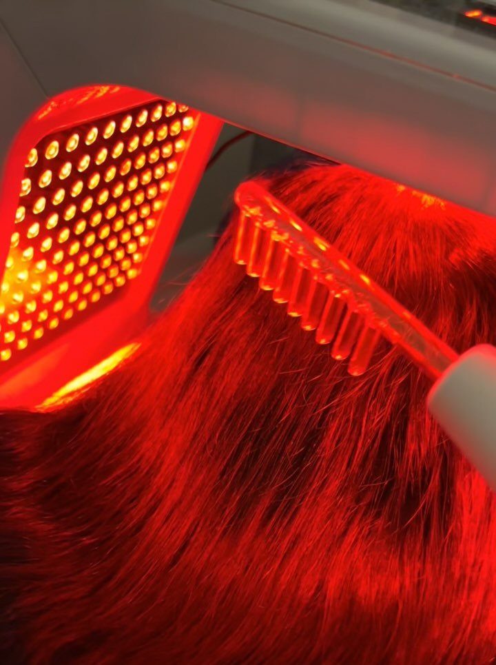 Red light therapy comb and LED panel being used on dark hair.