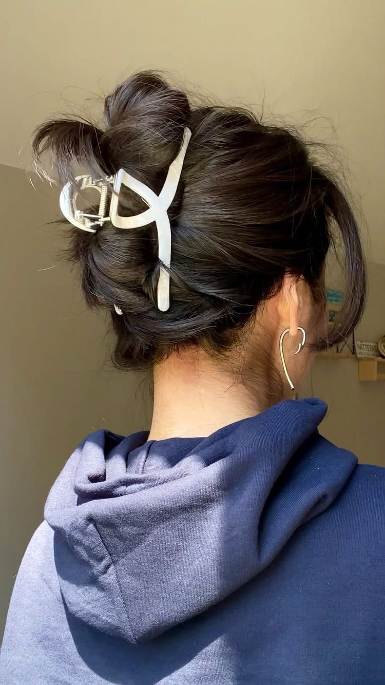 7 Hairstyle for Claw Clip Ideas, Messy Bun to Updo 4 Dark hair styled in a half top knot secured with a white claw clip.
