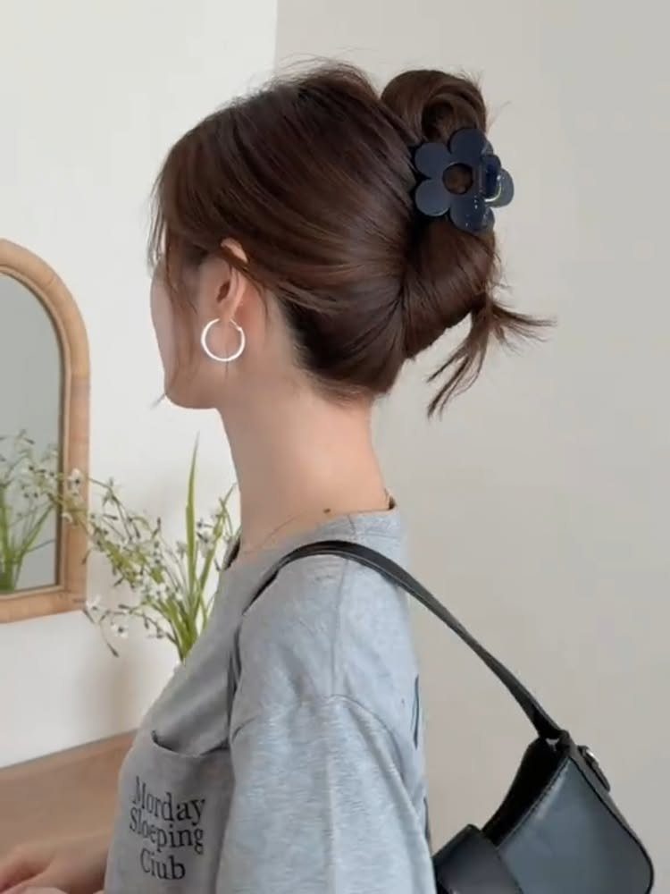 7 Hairstyle for Claw Clip Ideas, Messy Bun to Updo 3 Woman with brown hair in a twisted updo secured by a flower claw clip