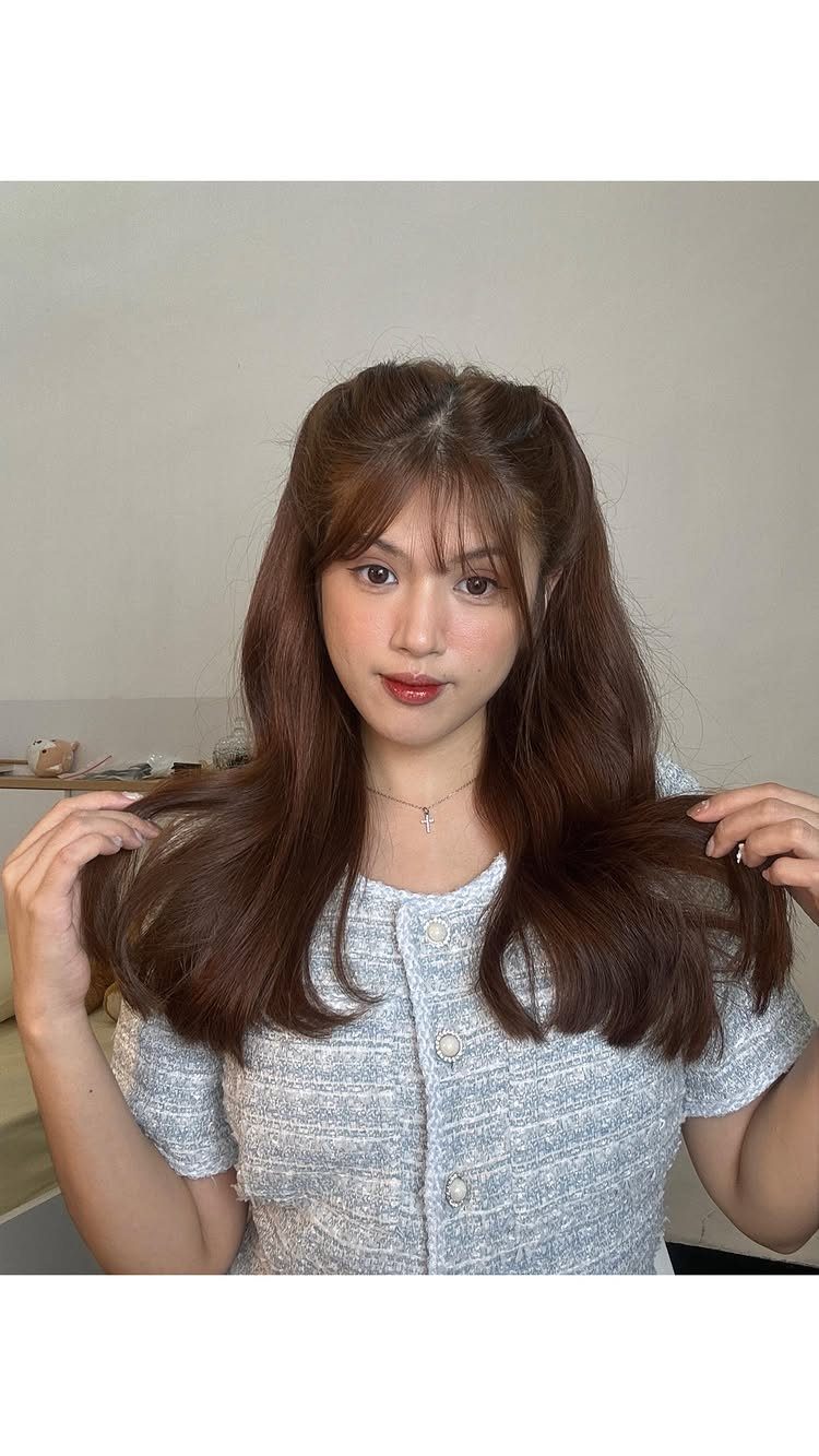 7 Hairstyles for Long Hair Down: Braids, Waves and Curls 5 Woman with long wavy brown hair and bangs wearing a grey textured top.