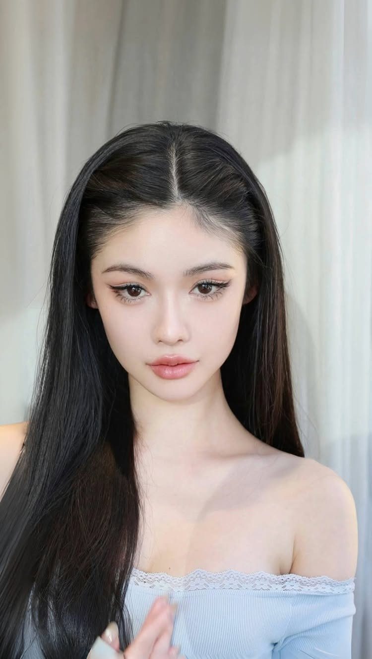 7 Hairstyles for Long Hair Down: Braids, Waves and Curls 4 Woman with long, pin straight black hair and a light blue off-the-shoulder top.