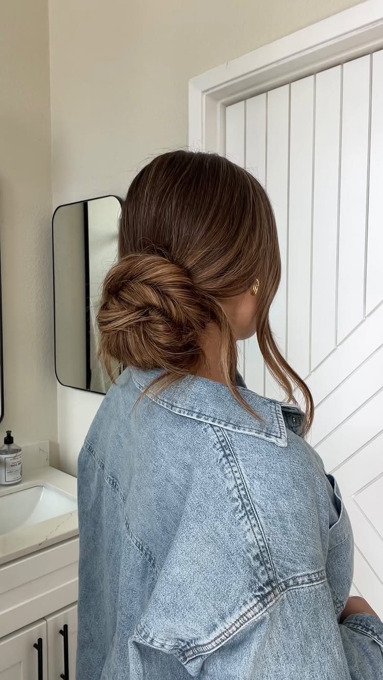 14 Hairstyles for Long Hair for Summer, Easy and Cool 3 Woman with brown hair styled in a twisted low bun wearing denim jacket
