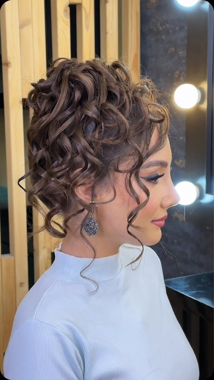 Woman with brown curly hair styled in a voluminous, elegant twisted bun updo.