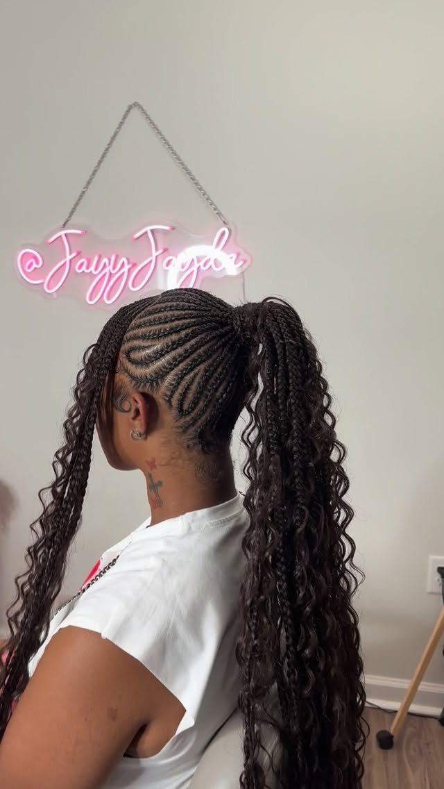 Person with long curly hair styled in cornrows and a high ponytail.