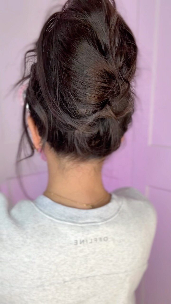 Dark brown hair styled in a high voluminous messy bun from behind