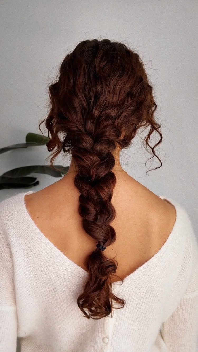 Long curly brown hair styled in a loose braid from the back.