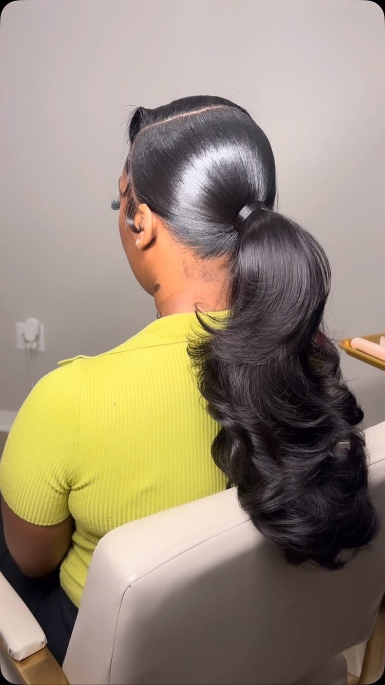 Woman with a sleek slicked-back ponytail and voluminous dark curls at the end.