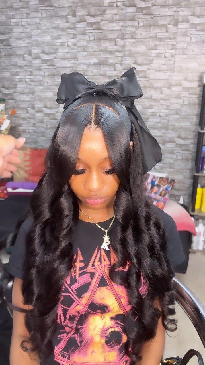 Woman with long wavy black hair wearing a large black bow on top.