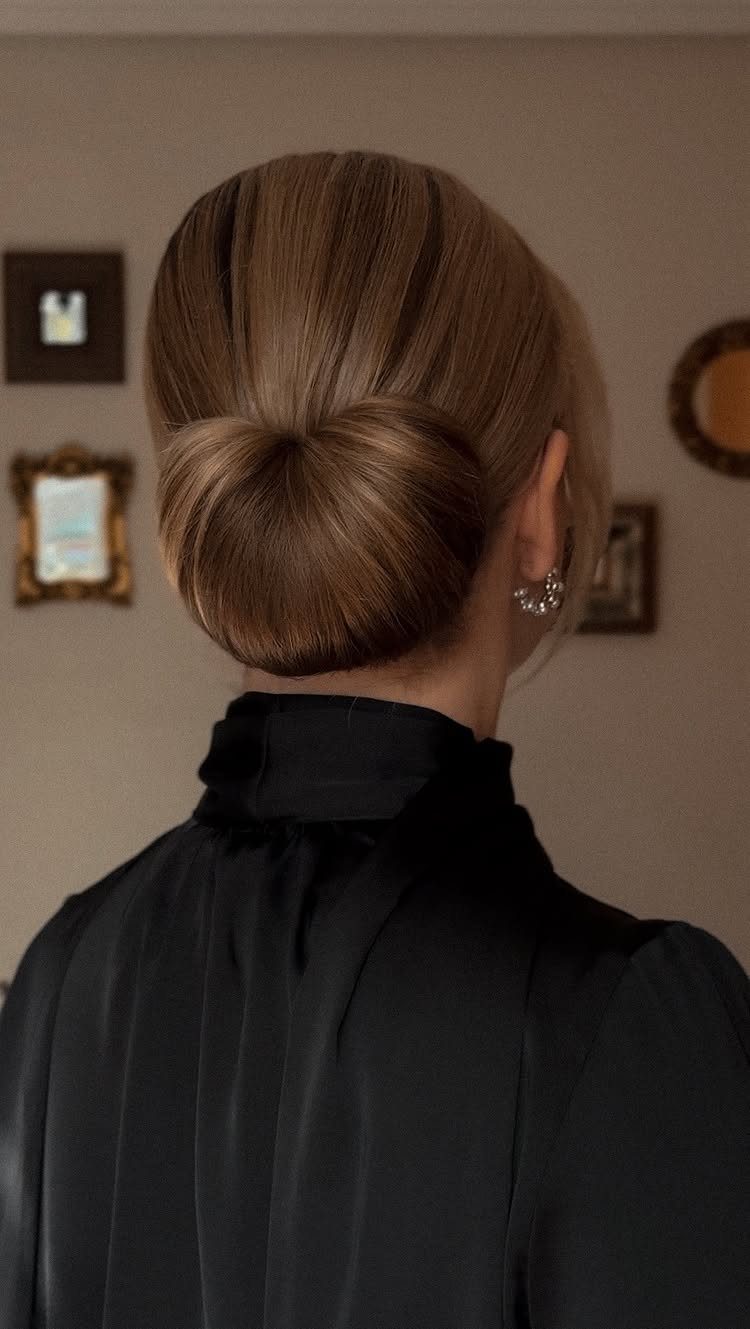Blonde woman with a sleek low bun styled to look like a bow.
