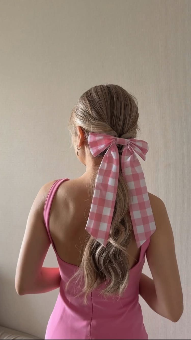 Blonde low ponytail tied with a large pink and white gingham checkered bow.