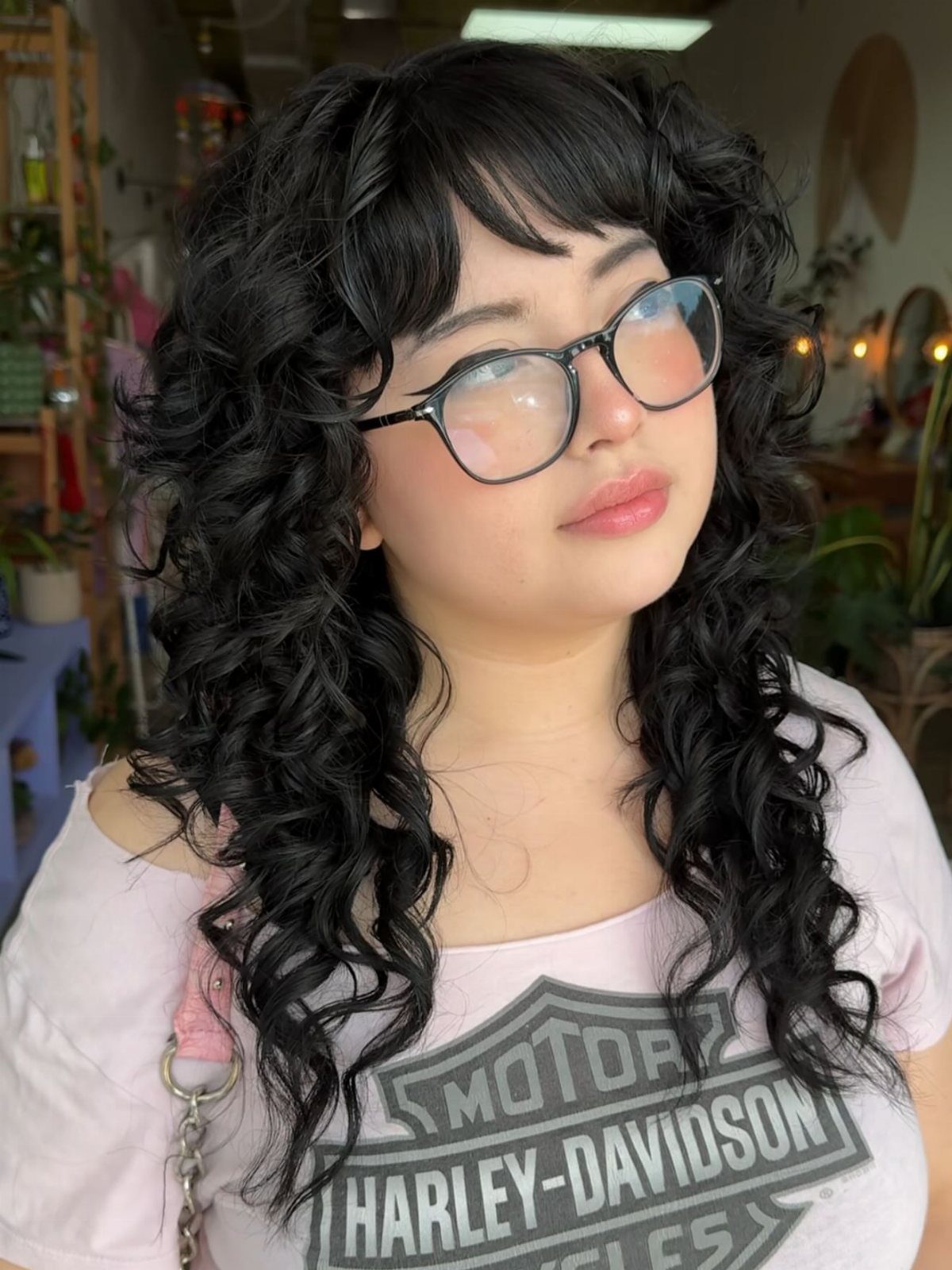 14 Hairstyles with Curly Bangs for Every Length and Curl 8 Woman with long black curly hair and full curly bangs wearing glasses.