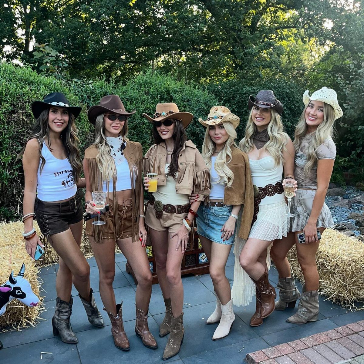 11 Hoedown Outfit Ideas for Boots, Denim and Dresses 1 Six women wearing western outfits with cowboy hats and brown leather boots.