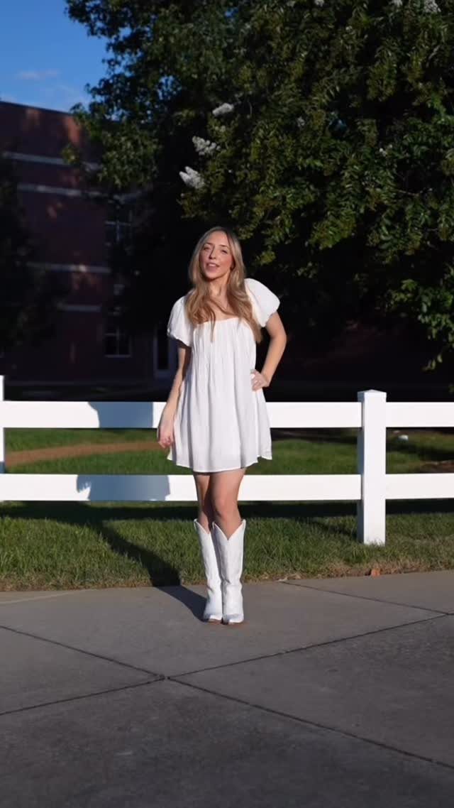 11 Hoedown Outfit Ideas for Boots, Denim and Dresses 4 Woman wearing a short white dress and white cowboy boots by a white fence