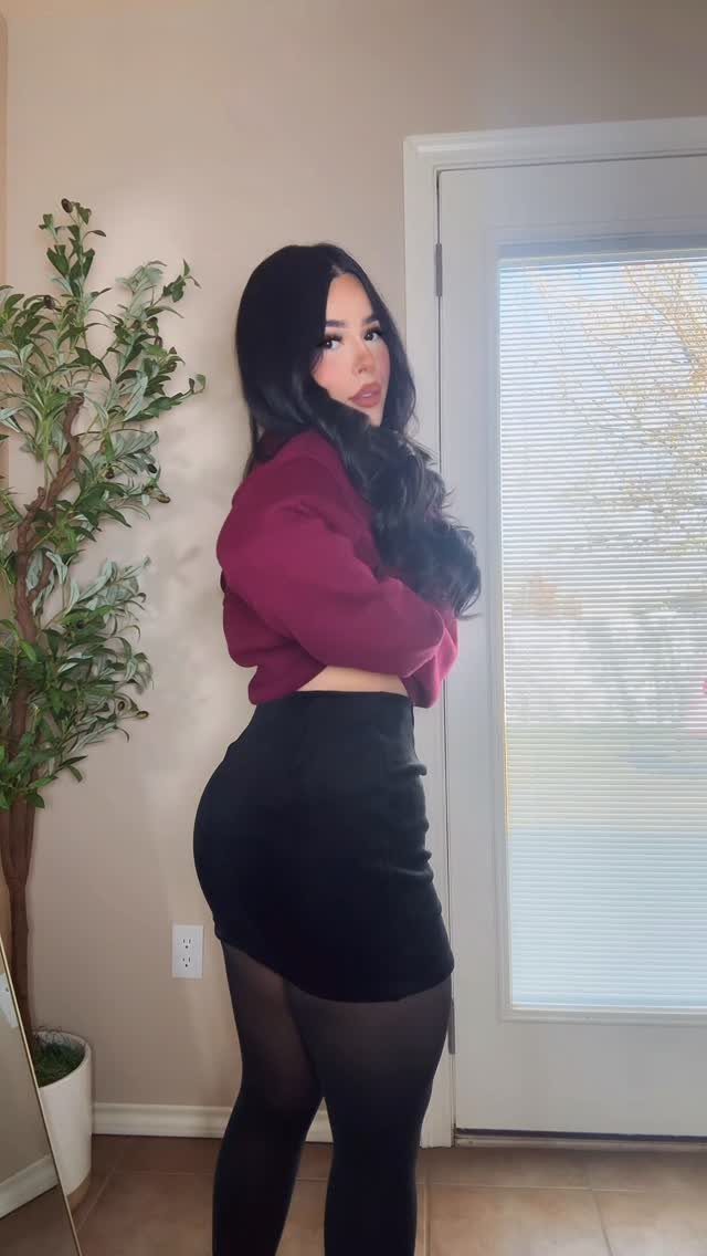 8 Holiday Party Attire for Women to Wear This Season 3 Woman wearing a burgundy cropped top and black velvet skirt for a holiday party.