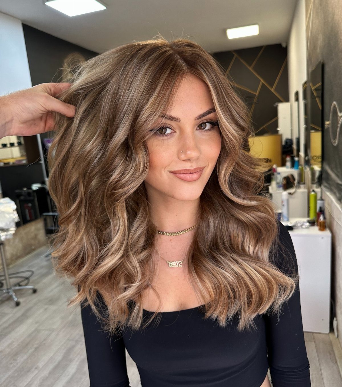 6 Honey Brown Hair with Highlights Ideas for Every Look 2 Woman with wavy honey brown hair and caramel balayage highlights in a salon