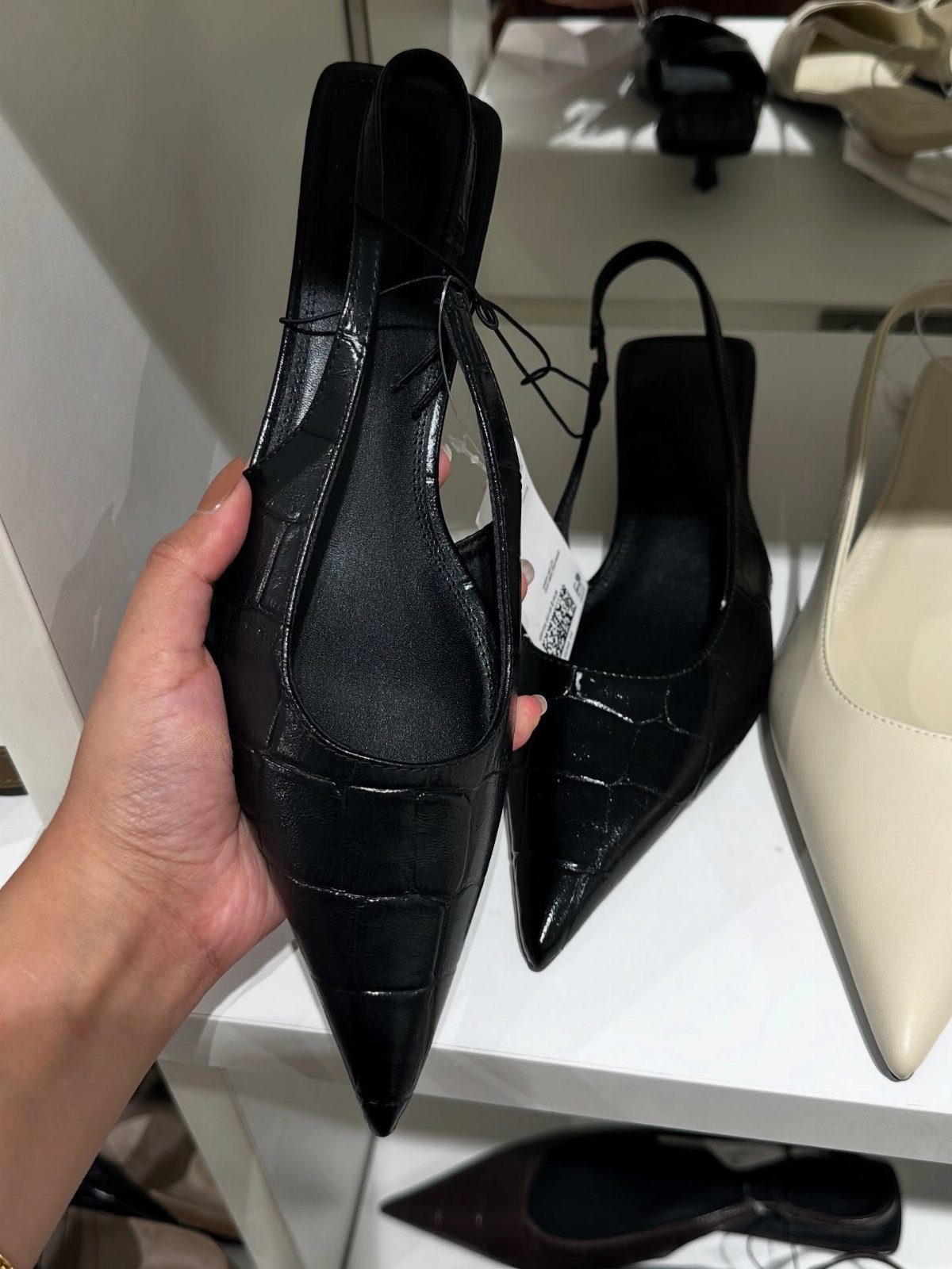 Kitten Heel Shoes for Women: 10 Ideas and Outfits 5 Black croc-embossed pointed-toe kitten heel pumps held in a hand on store shelves.