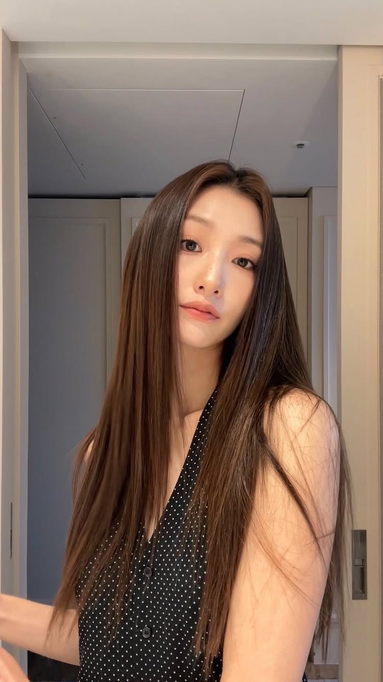 Korean Glass Hair: 6 Sleek and Shiny Styles to Try 3 Woman with long, straight, glossy brown hair wearing a polka dot top.