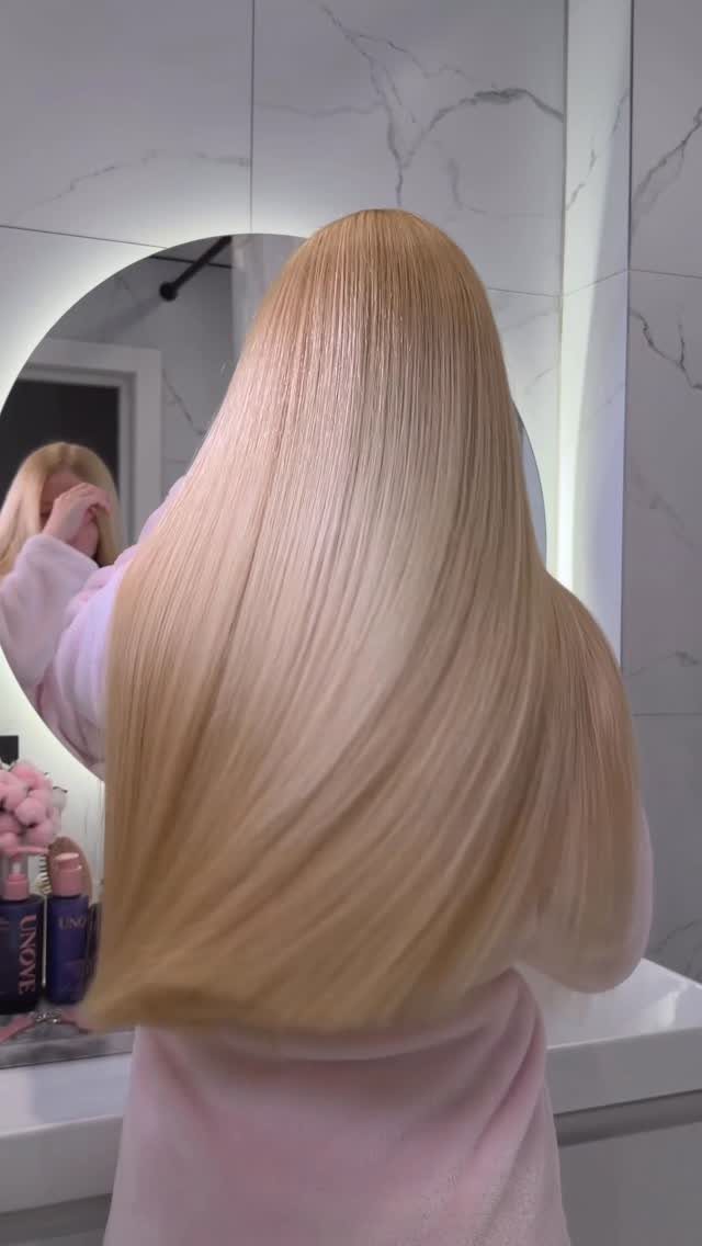 Korean Glass Hair: 6 Sleek and Shiny Styles to Try 5 Long, straight, glossy blonde hair reflecting light in a white marble bathroom.